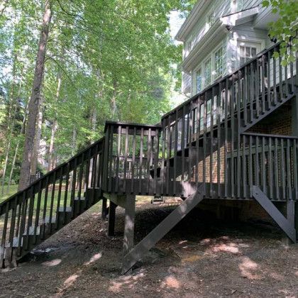 Wooden deck and stairs beside a house in a wooded yard