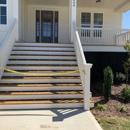 Front porch entrance with stairs blocked by yellow caution tape on a sunny day
