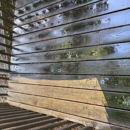 Wet wooden slats with reflections of trees and sky, plus a lower wooden bench in the foreground