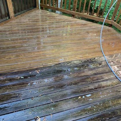 Weathered wooden deck with a darker, mossy wet section and railing in the background