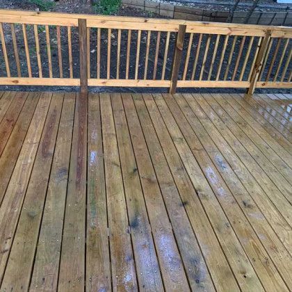 Wet wooden deck with railing and reflective puddles