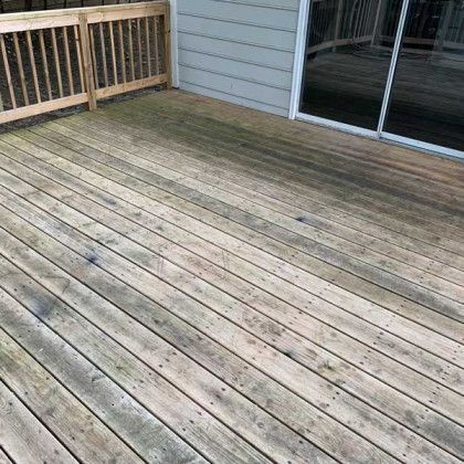 Weathered wooden deck beside a house, with sliding glass doors and railing.
