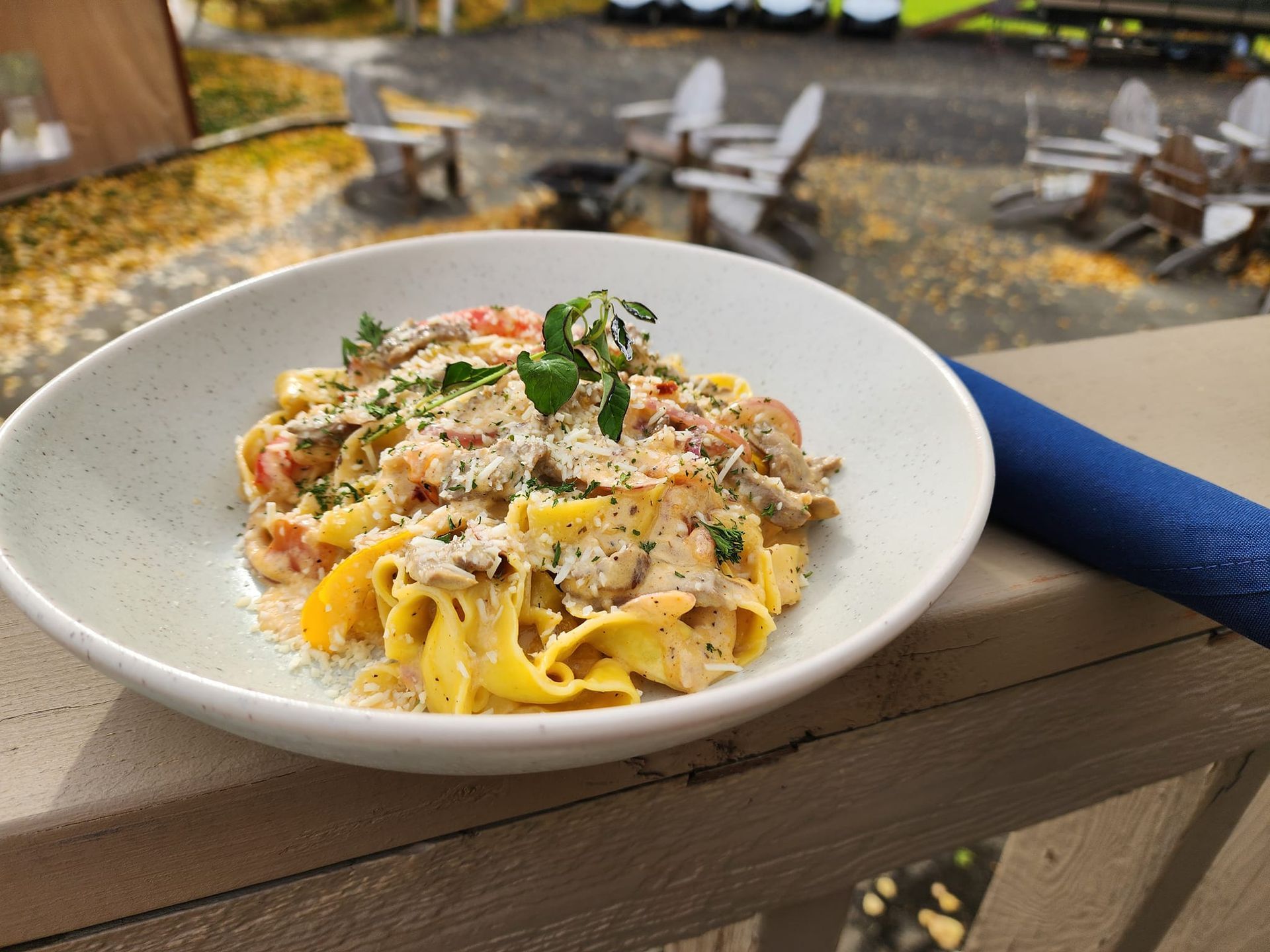 A bowl of pasta is sitting on a wooden table.