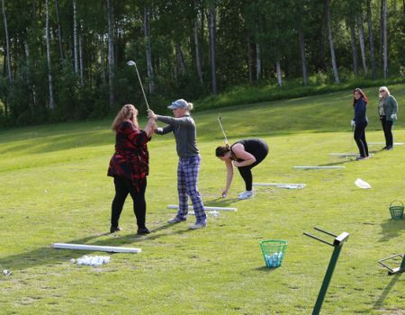 A group of people are practicing golf on a lush green field.