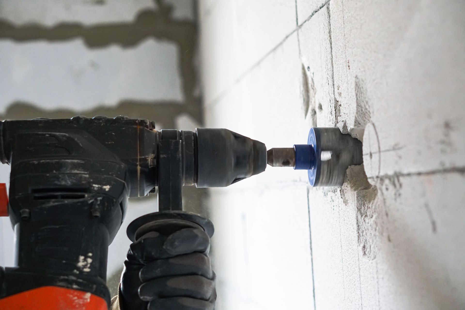 Un taladro eléctrico haciendo un agujero en una pared de azulejos blancos.