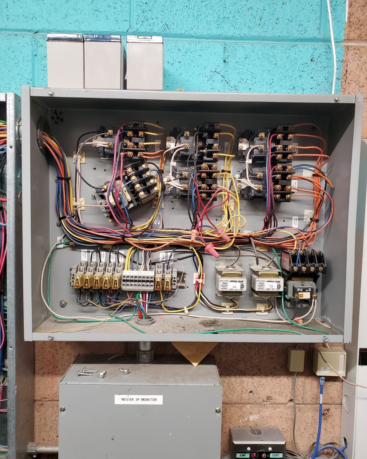 Electrical control panel with wires, relays, and components mounted inside a metal box.