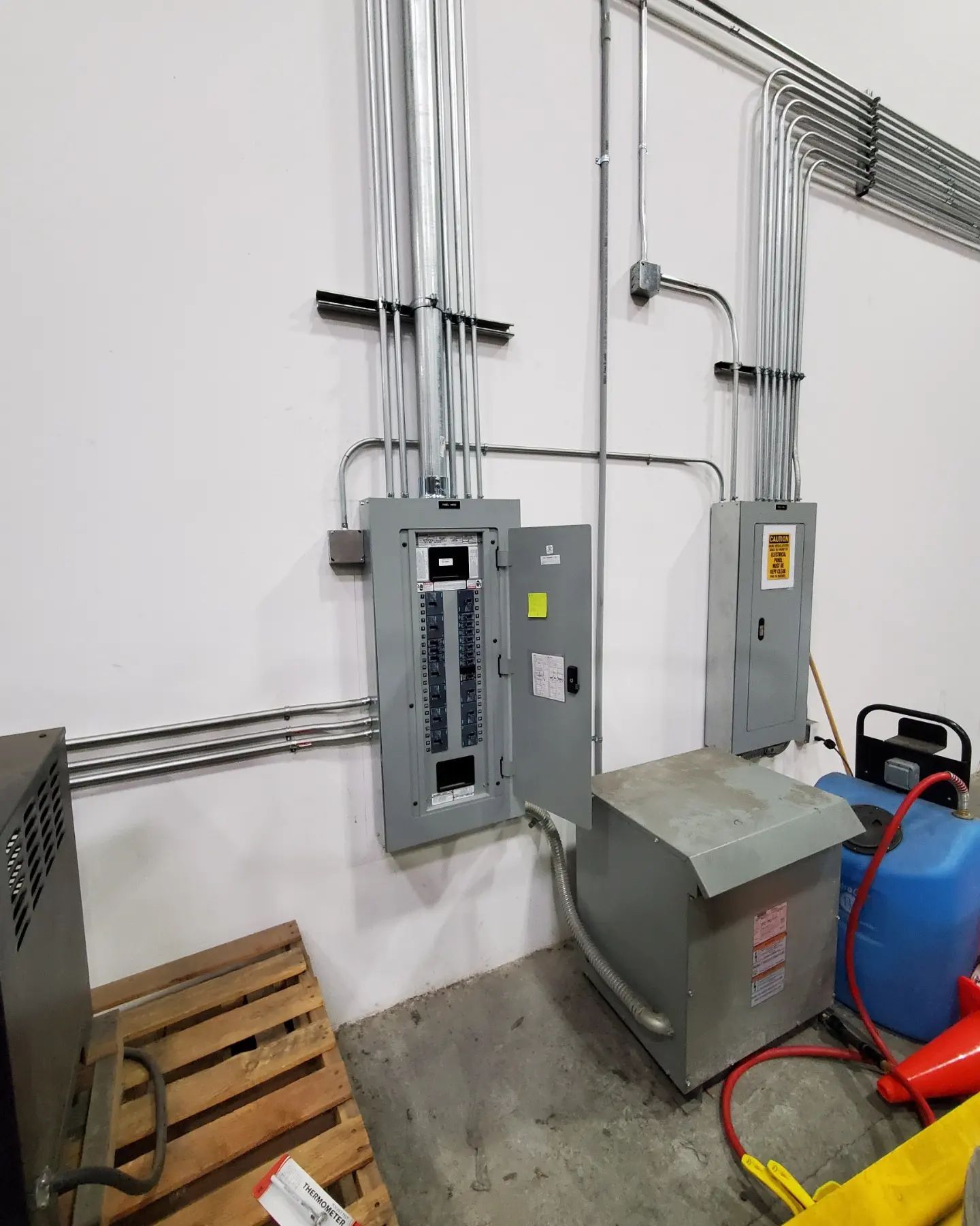 Electrical panel and transformer on a white wall in an industrial setting.