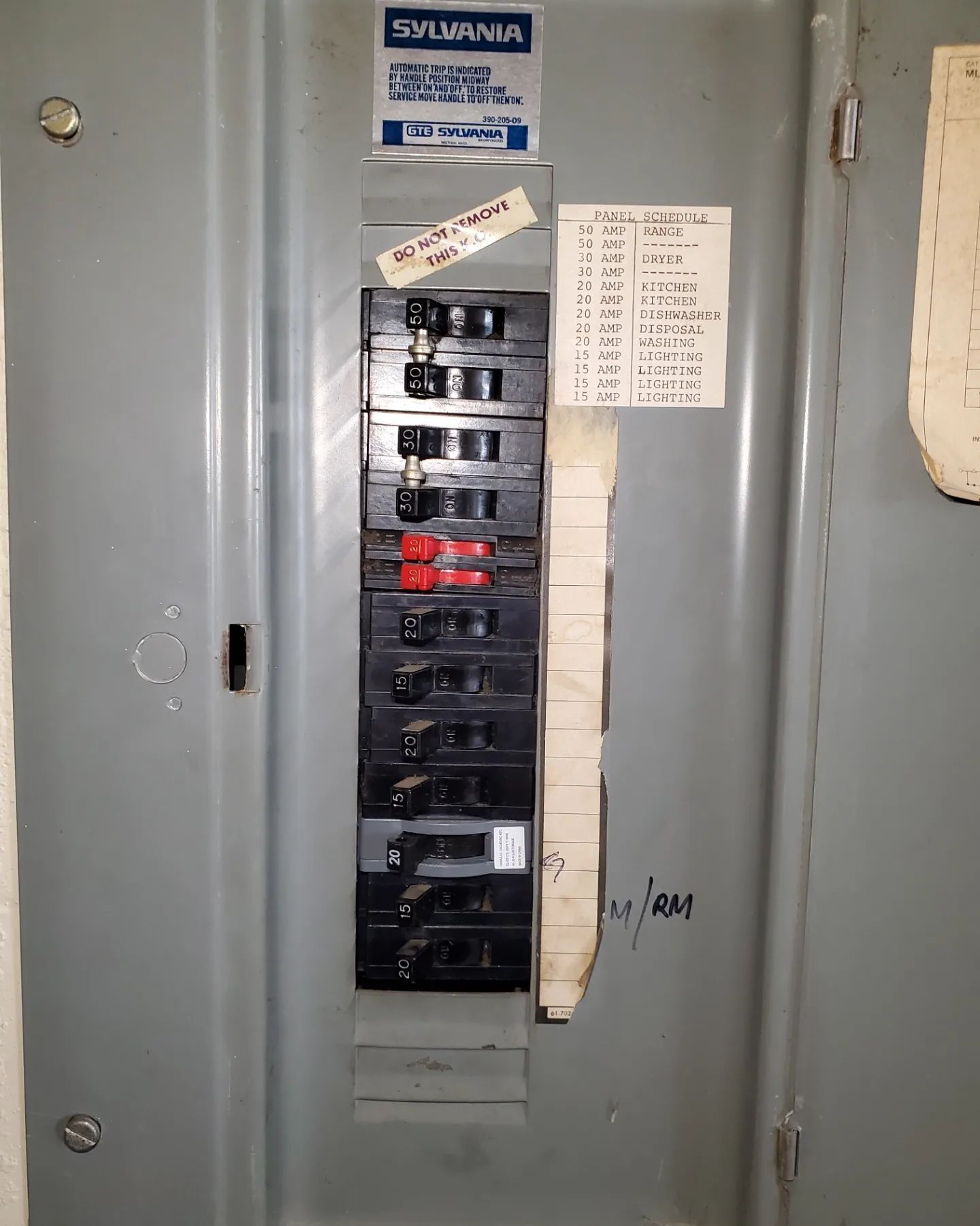Electrical panel with labeled circuit breakers in a grey metal cabinet.