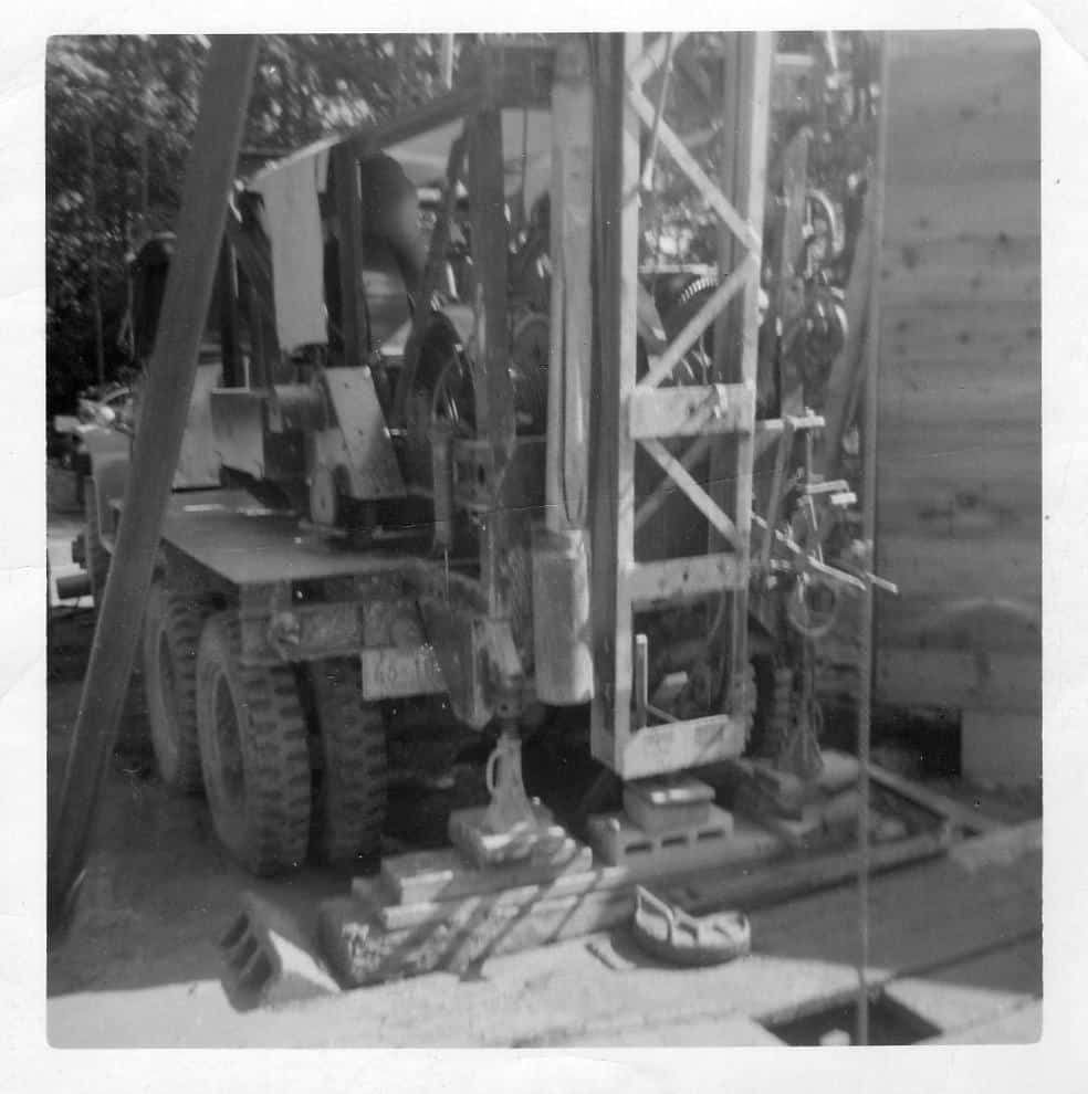 A black and white photo of a truck with a crane attached to it.