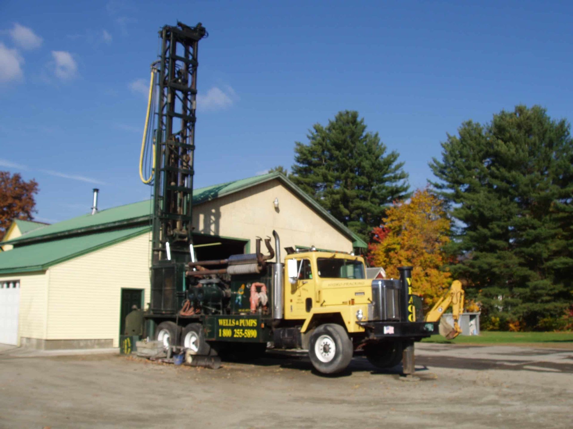 A yellow truck is parked in front of a house with a green roof from Wragg Brothers Well Drilling