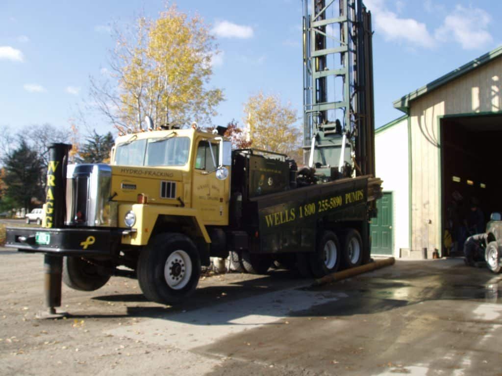A wells truck is parked in front of a building from Wragg Brothers Well Drilling