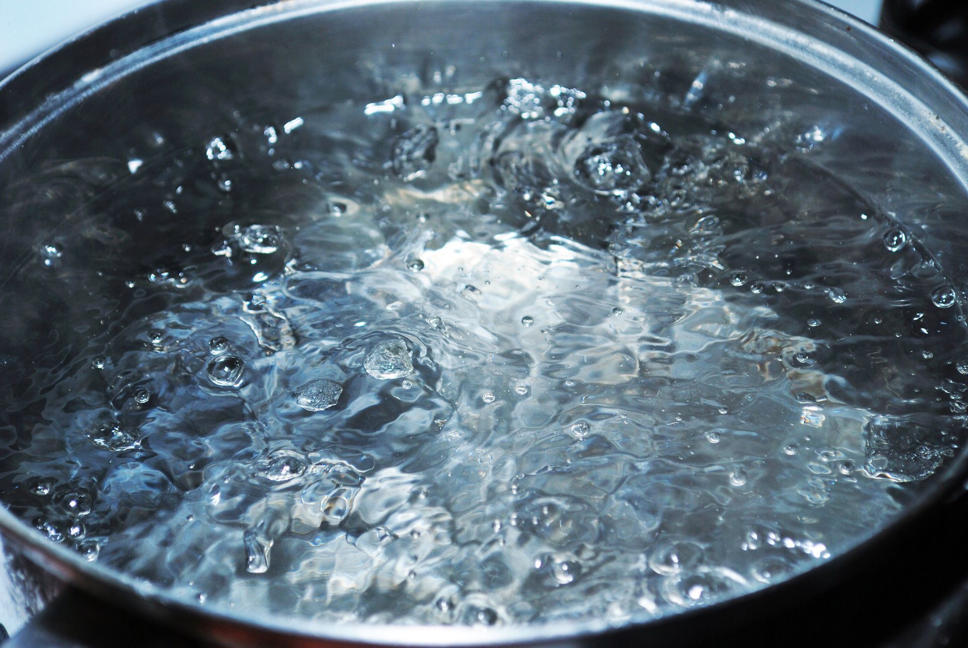 Boiling water swirling in a metal pot, with steam and bubbles visible