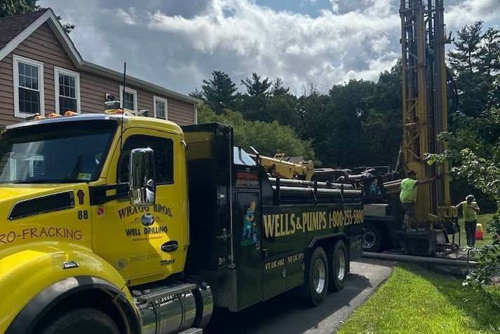 A yellow truck is parked in front of a house.