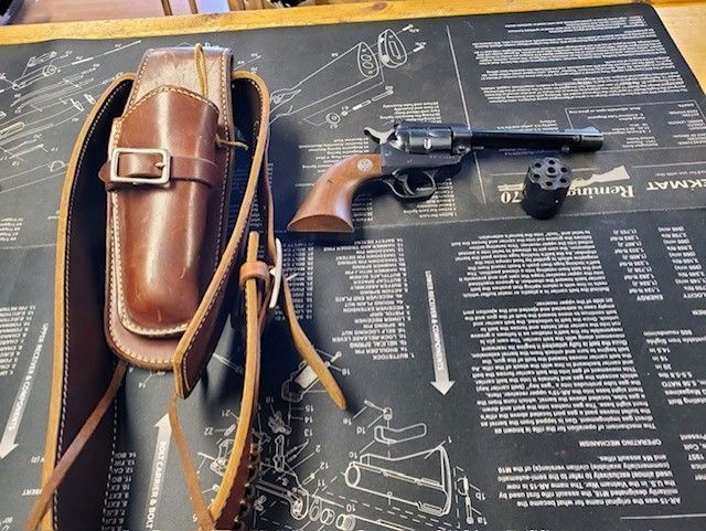 Revolver and brown leather holster on a black gunsmithing mat with diagrams.