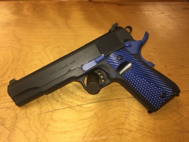 Black handgun with blue grip on a wooden surface.