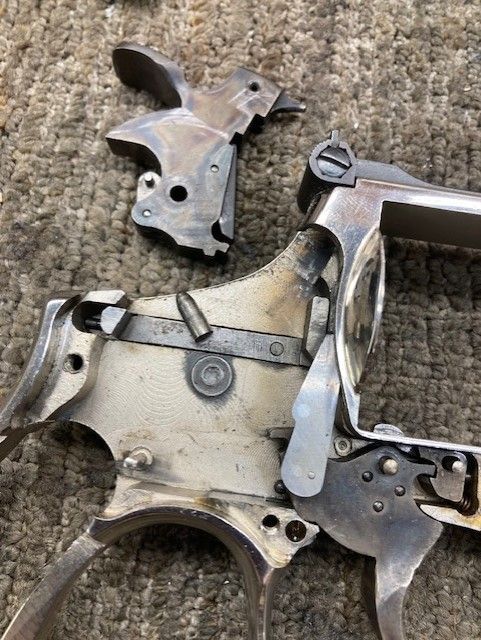 Close-up of disassembled silver handgun parts on a beige carpet