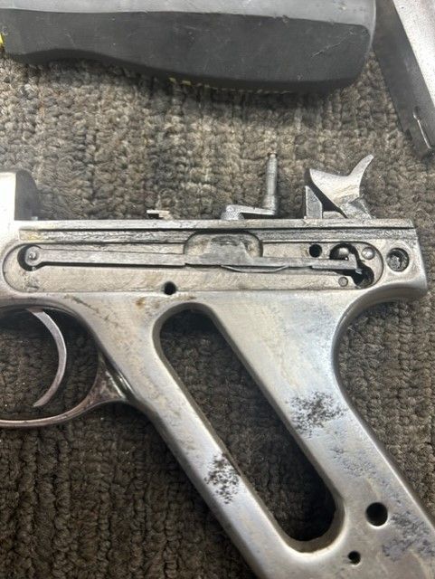 Close-up of a worn metal firearm frame on a dark textured surface.