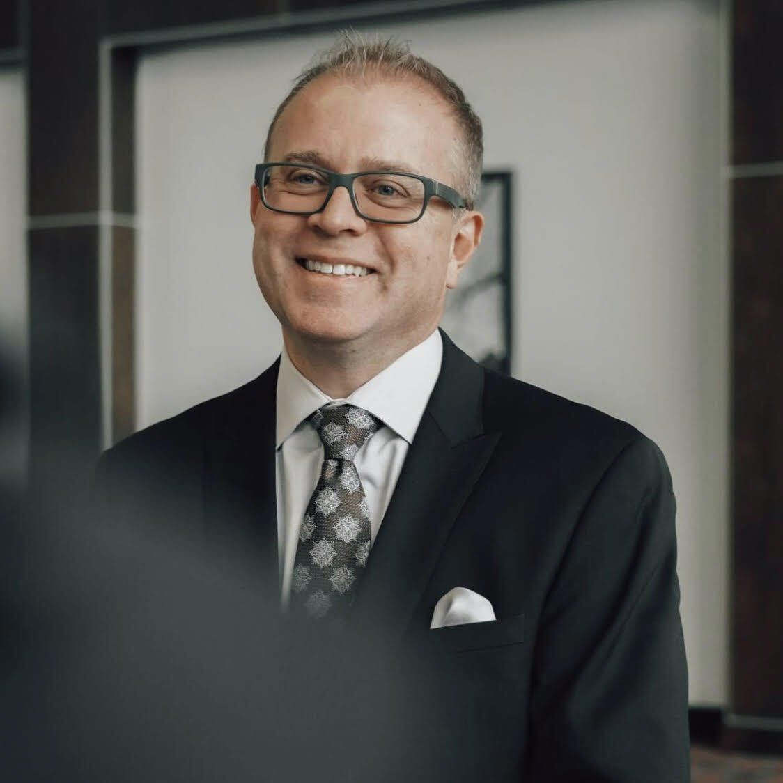 A man in a suit and tie is smiling for the camera