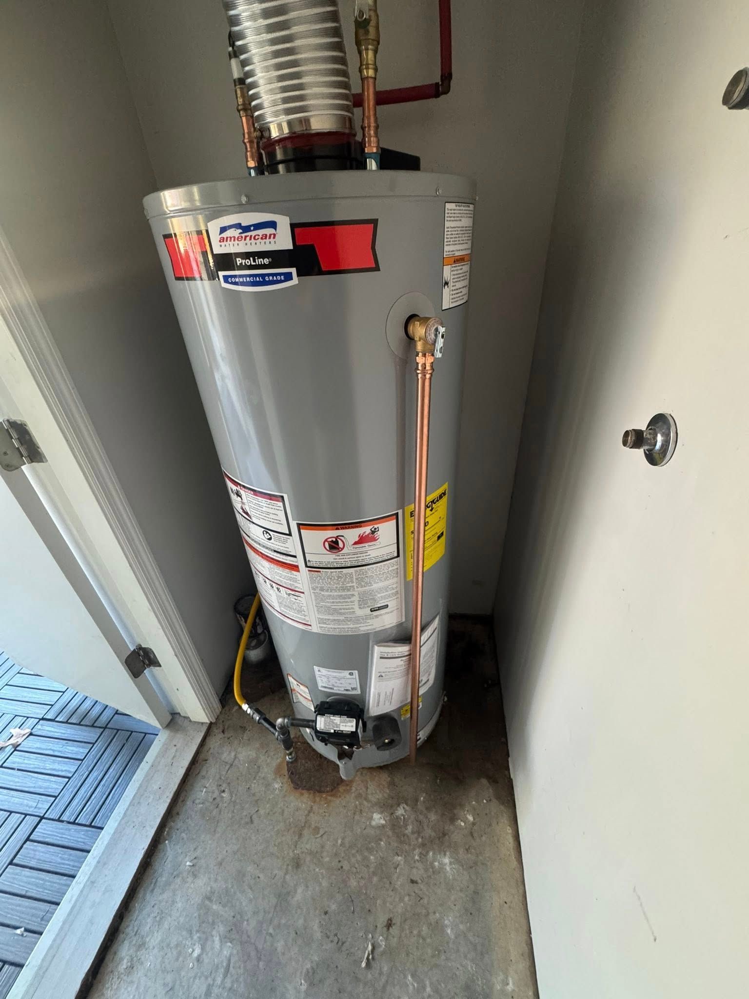 Water heater in a narrow utility closet with visible pipes and insulation ducting.