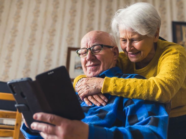 An elderly couple is looking at a tablet together.