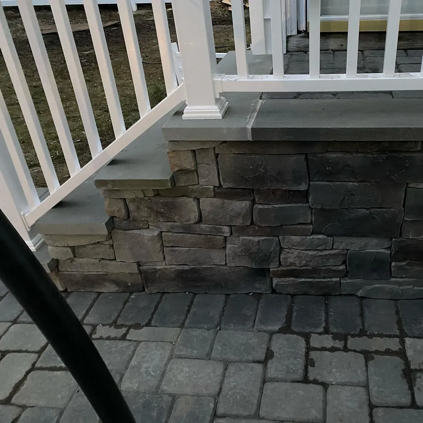 Trench dug in a grassy yard, leading to a house with black siding, and an electrical box.