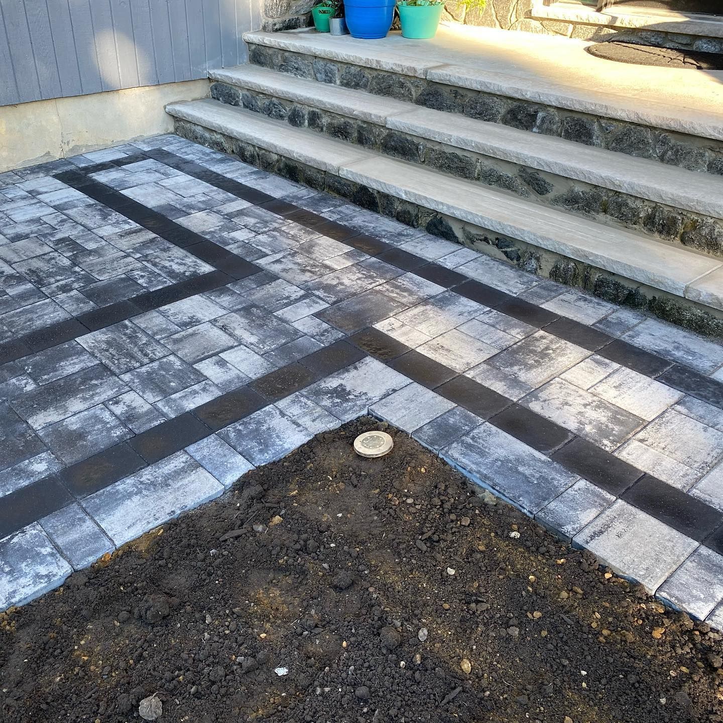 Two electricians working on an electrical panel outside a building. One holds a cable.