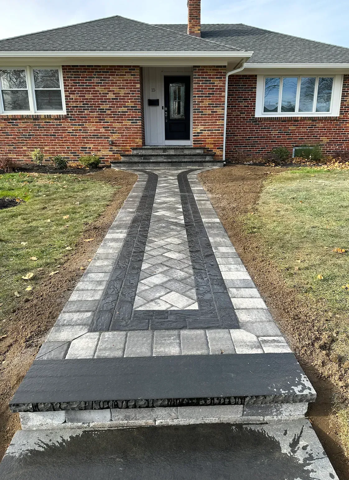 Brick house with a brick and paver pathway leading to the front door, with a step at the entrance.