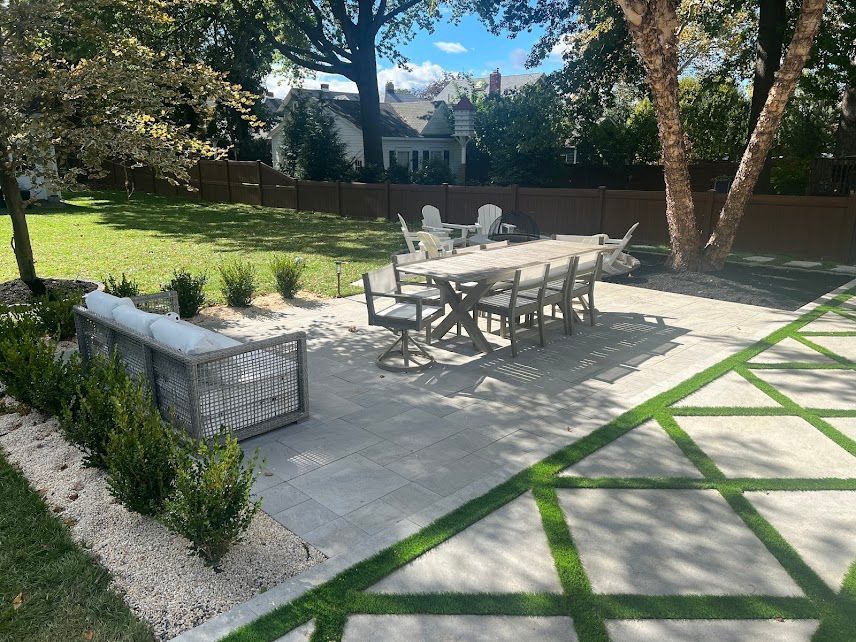 A partially built patio with gray stone tiles. Walls are wrapped in Tyvek, and a window is visible.