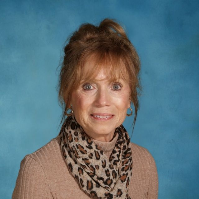 A woman wearing a brown sweater and a leopard print scarf