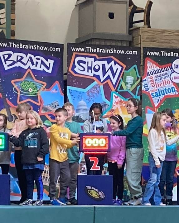 A group of children standing in front of a brain show sign