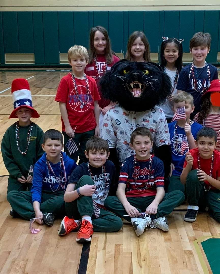 A group of children are posing for a picture with a mascot.