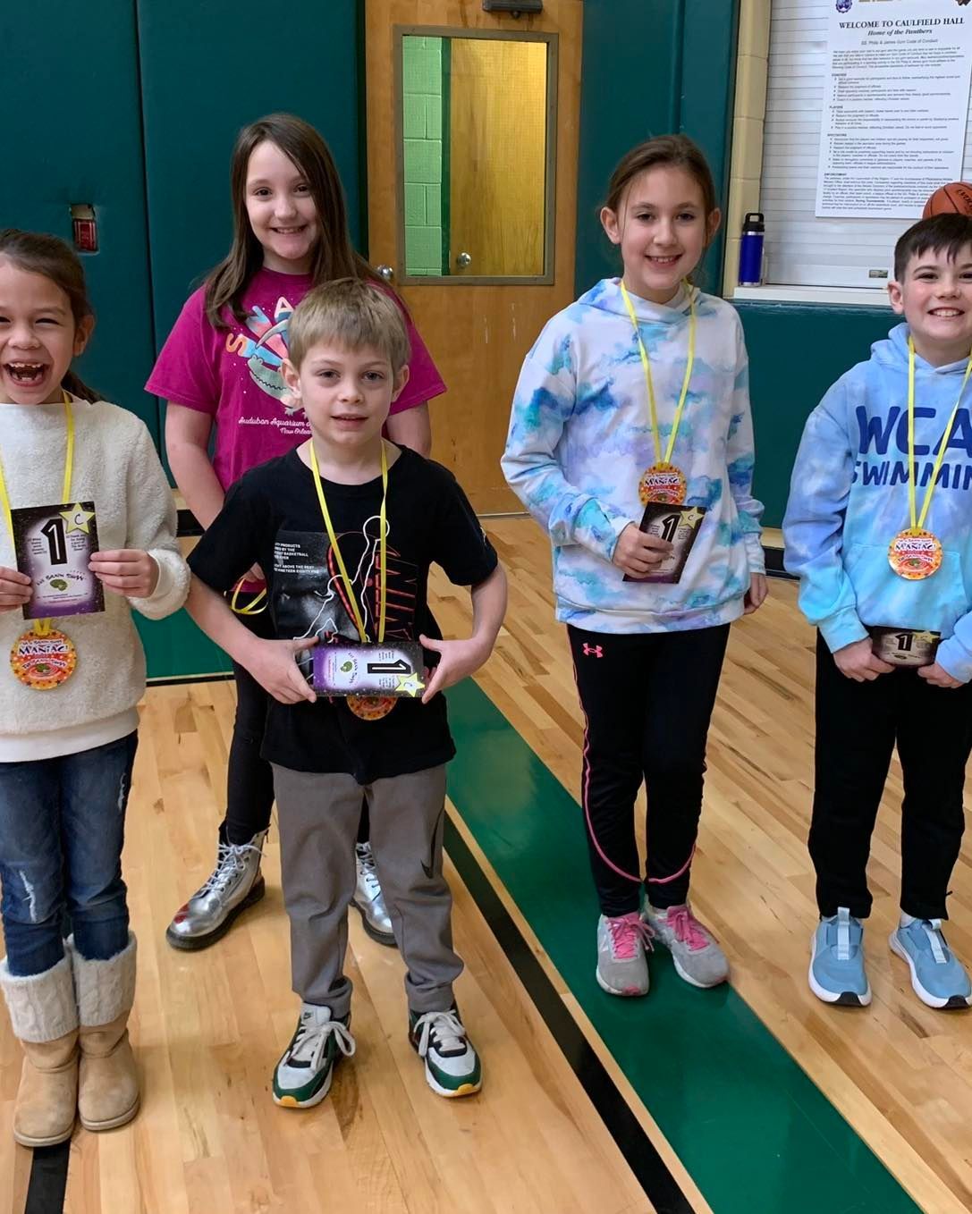 A group of children are posing for a picture in a gym.