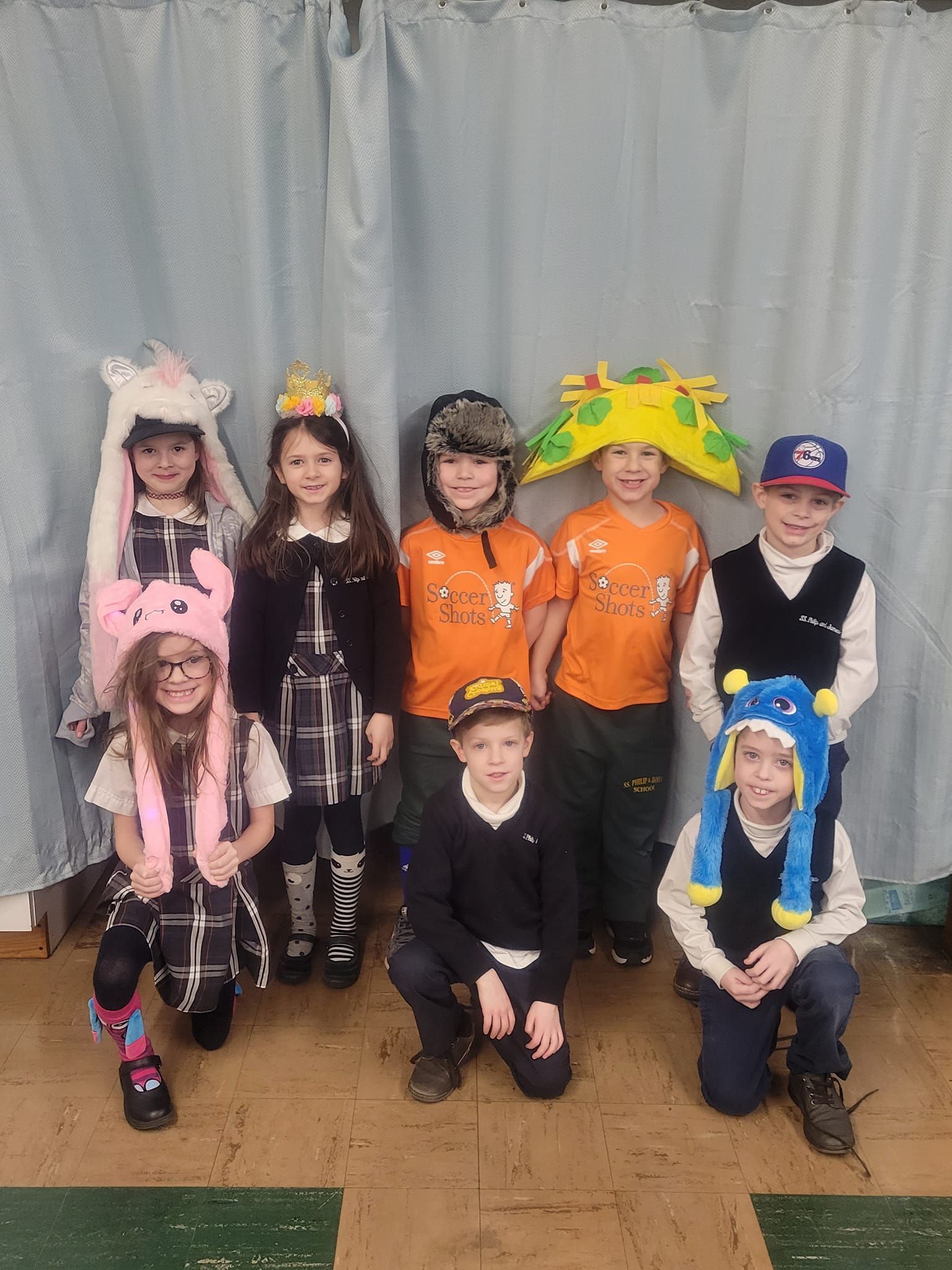 A group of children wearing hats are posing for a picture.