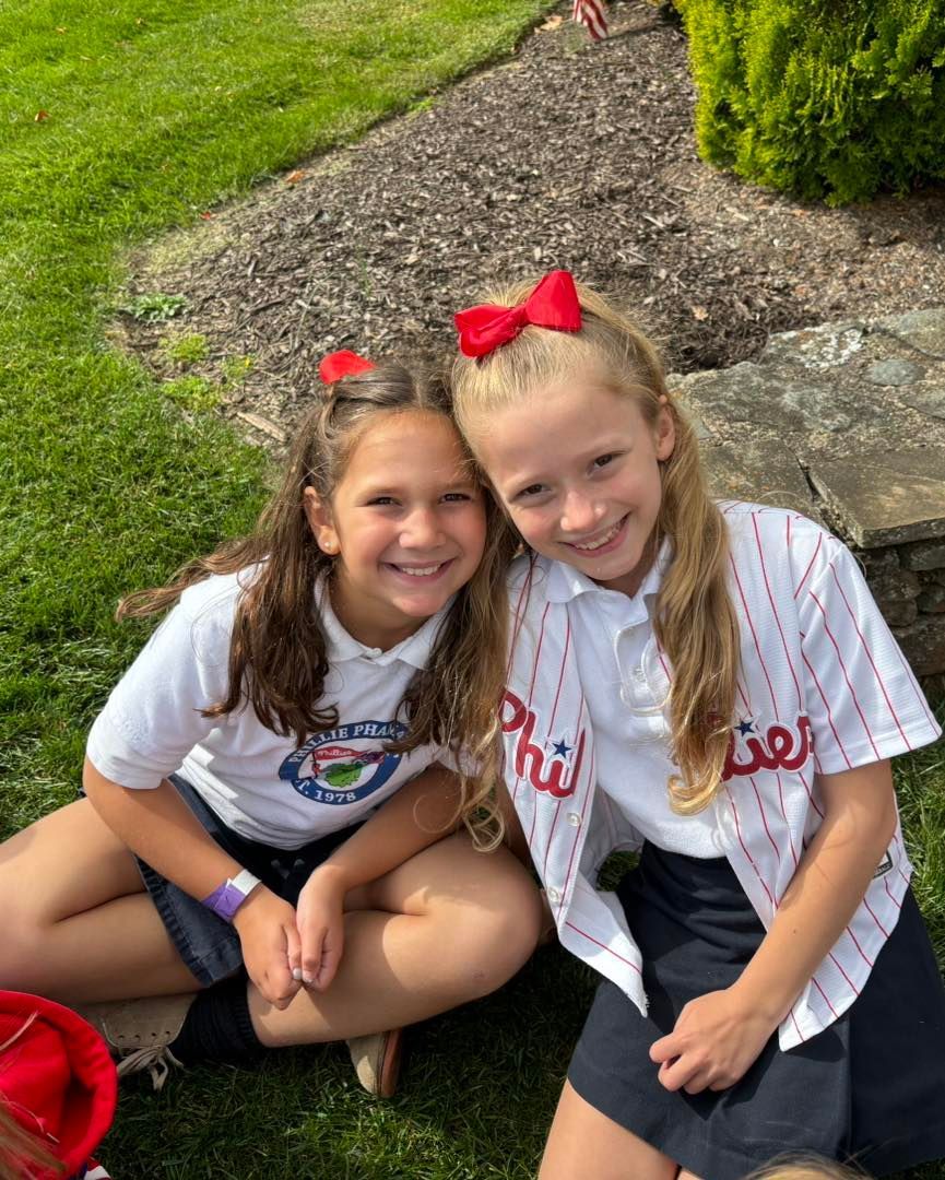 Two girls smiling wearing Philadelphia Phillies shirts.