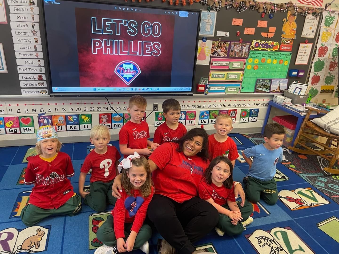 A group of children are sitting on the floor in a classroom.