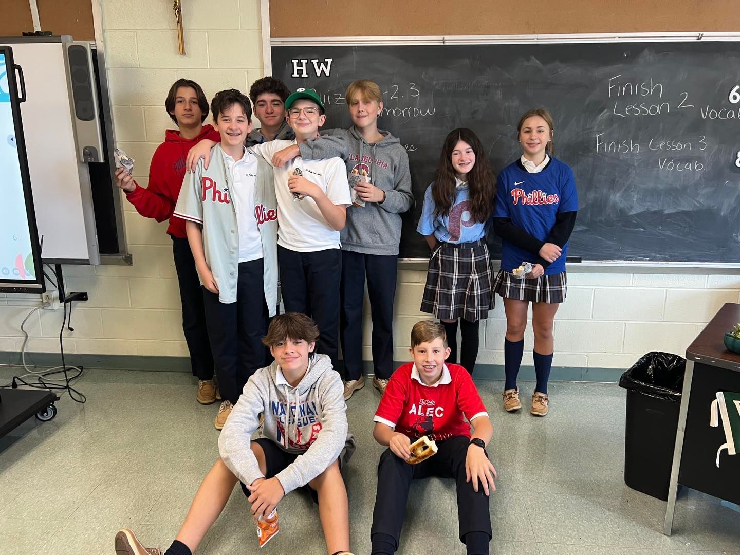 A group of young people are posing for a picture in a classroom.