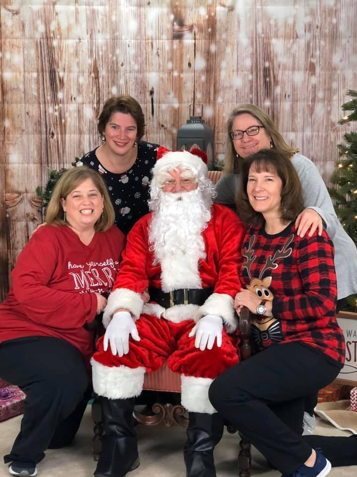 A group of women are posing for a picture with santa claus.