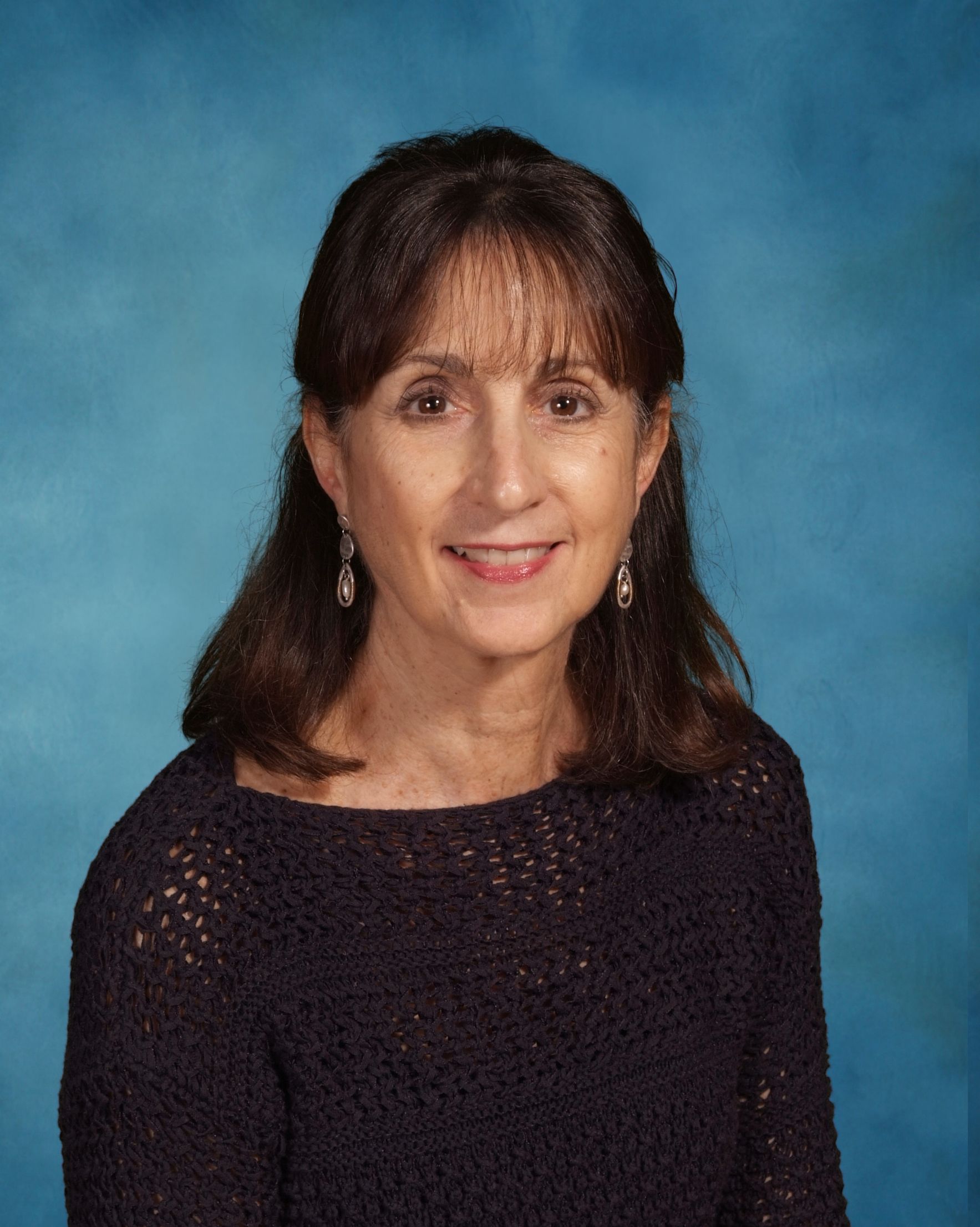 A woman is posing for a picture in front of a blue background.