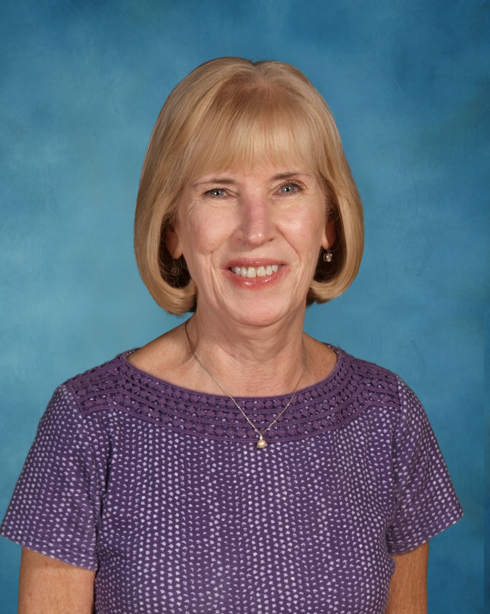 The woman is wearing a purple shirt and smiling for the camera.