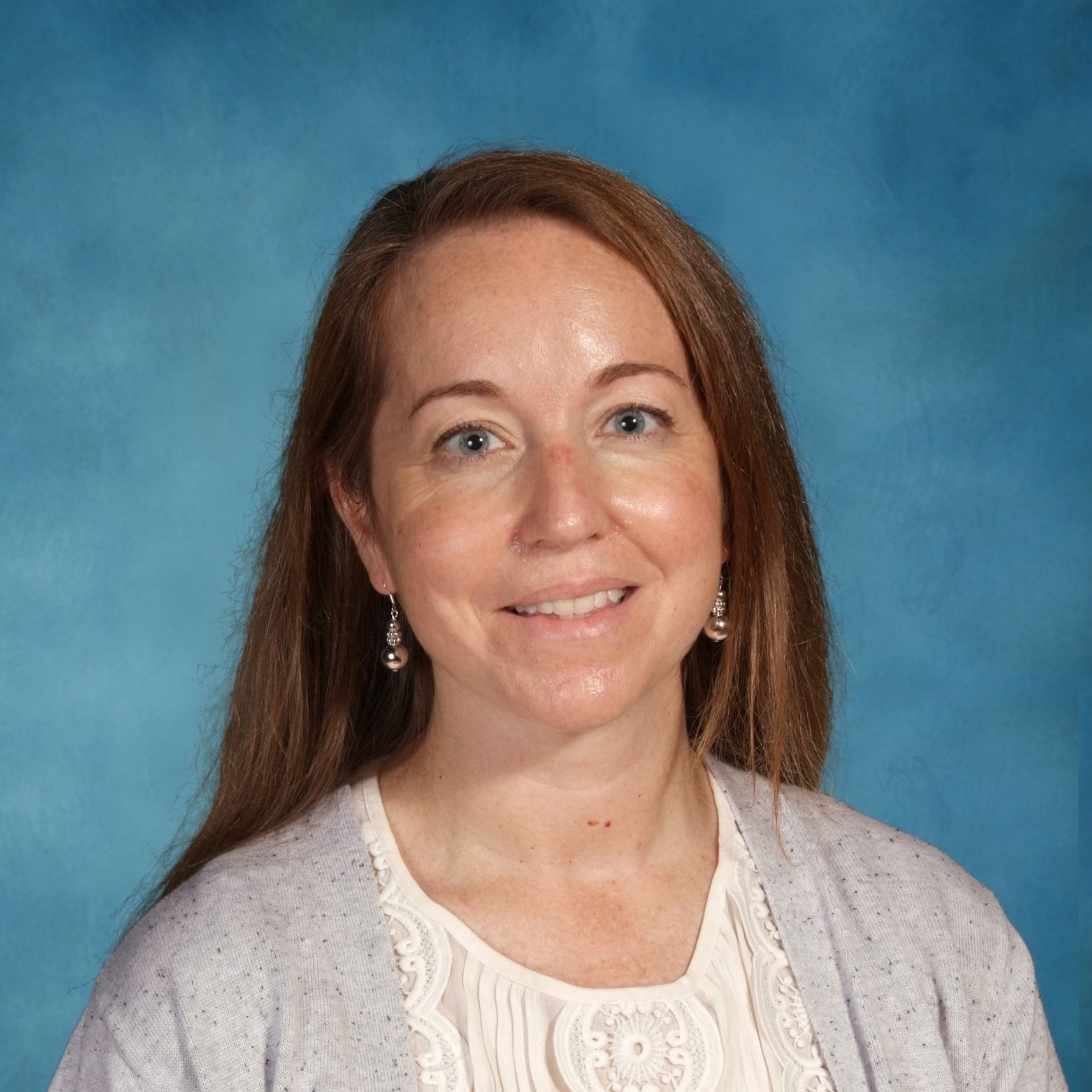 A woman is smiling for a picture in front of a blue background.