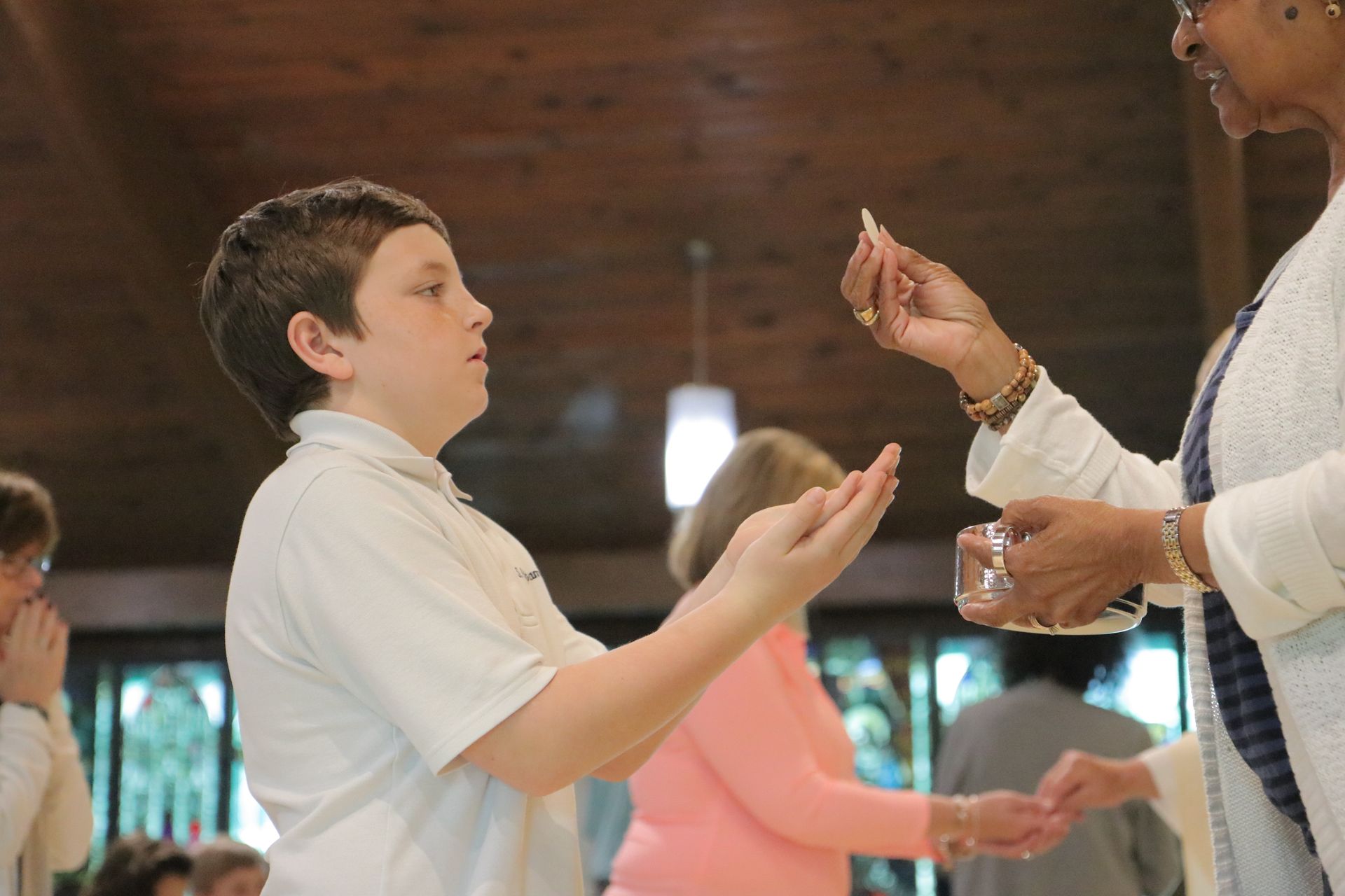 A boy is receiving communion from a woman in a church.