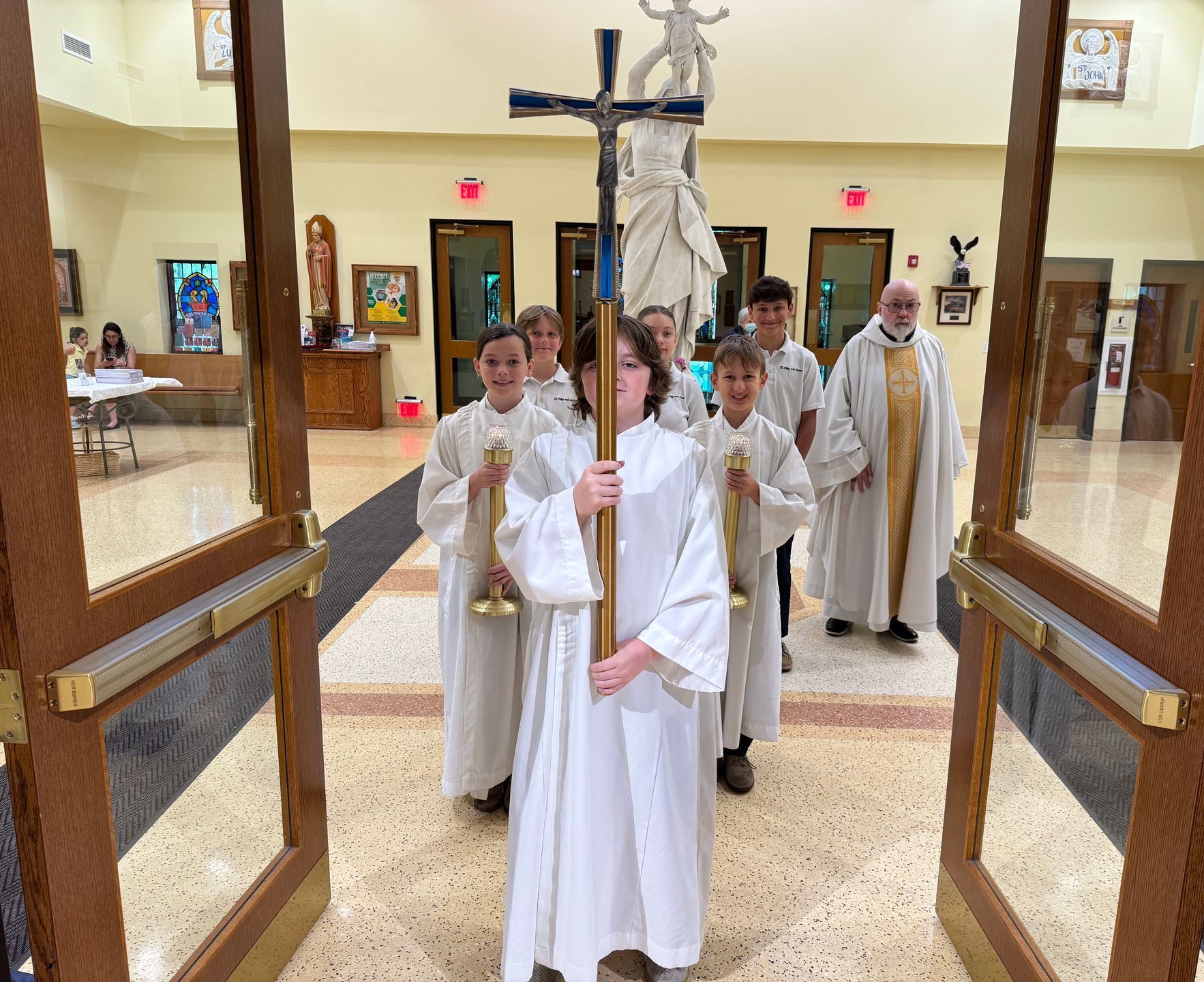 A group of children are carrying a cross in a church.