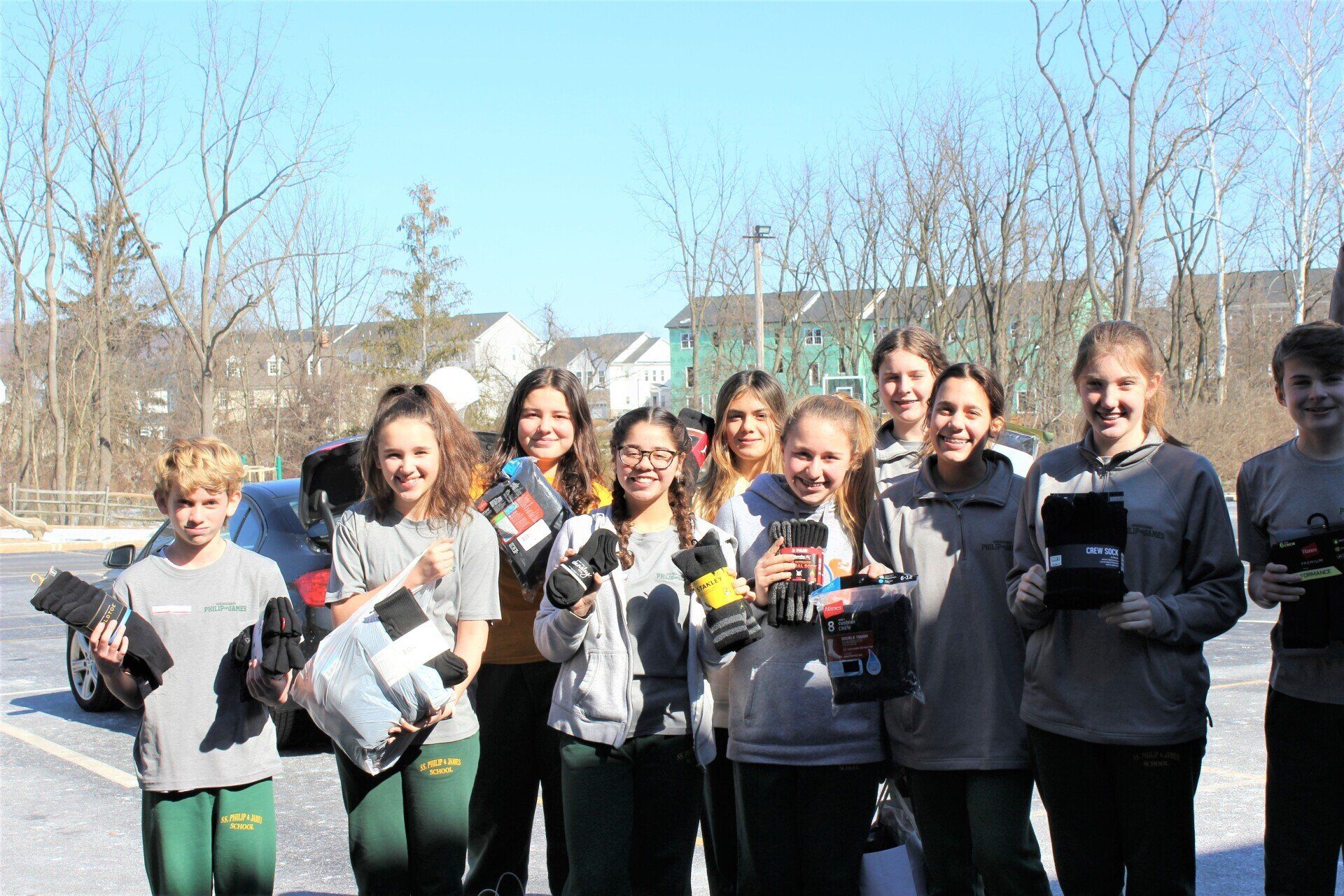 A group of young people are standing next to each other in a parking lot.