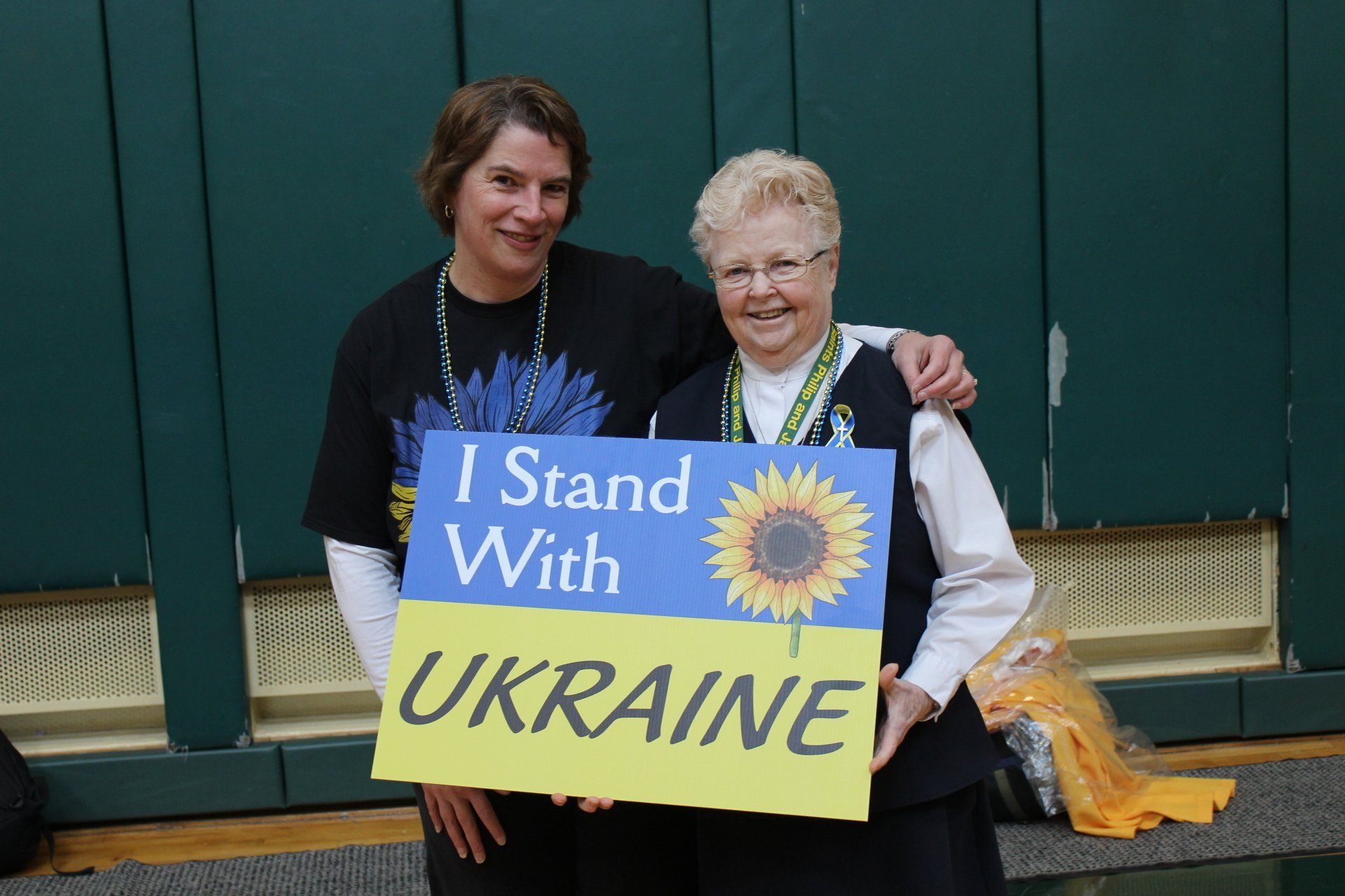 Two women holding a sign that says i stand with ukraine