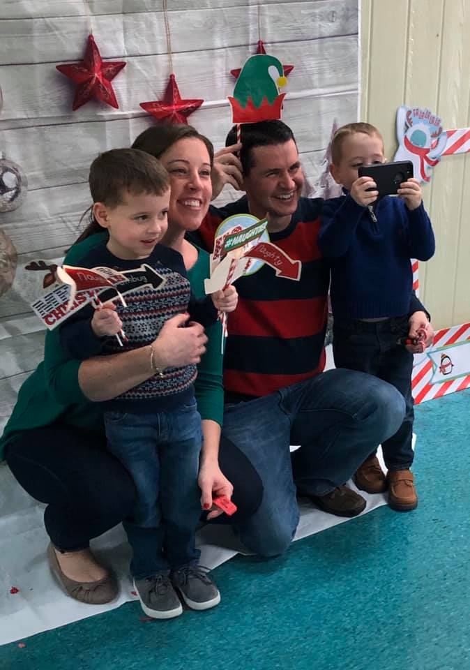 A family is posing for a picture with christmas props.