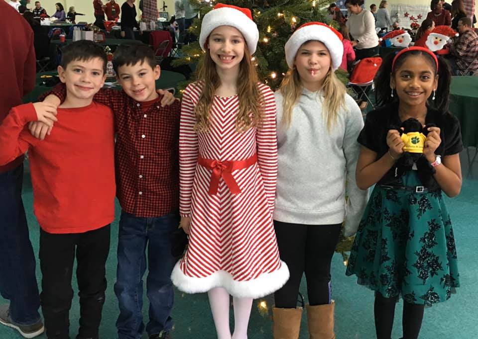 A group of children are posing for a picture in front of a christmas tree.