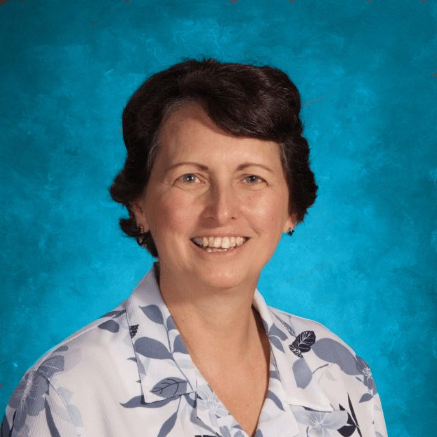 A woman in a floral shirt is smiling in front of a blue background