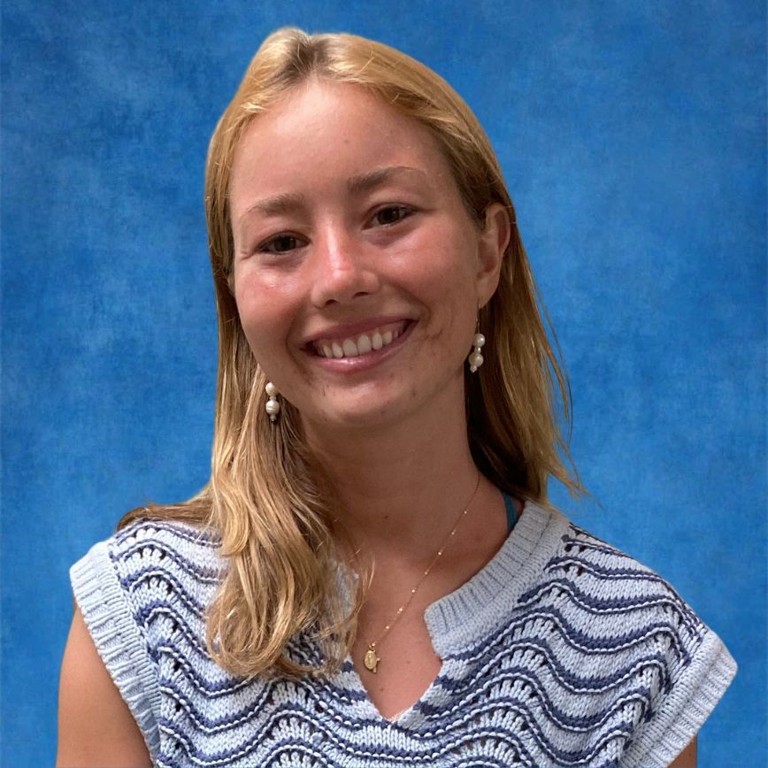 A woman wearing glasses and a necklace smiles for the camera