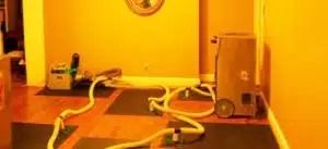 Coiled cables on the floor beside a wall outlet and small metal box in a warm-lit room