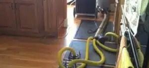 Kitchen floor with a vacuum hose and attachments near cabinets and a doorway